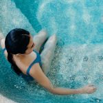 Aerial view of a woman in a blue swimsuit lounging in a swimming pool, capturing a serene moment.
